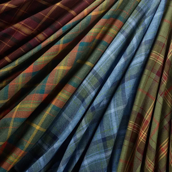 The Grampian Faux Wool fabric offers draped tartan patterns in rich hues like red, brown, green, and blue. Its diagonal designs and vibrant textures give a warm and inviting look.