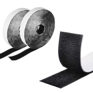 Two rolls of black adhesive hook and loop fastener tape are unrolled, revealing one side with hooks and the other with loops. The tape appears glossy, with each roll neatly coiled, and the cut section shows the fastening mechanism.