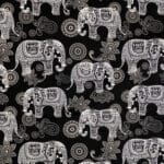 Intricate white and beige patterned elephants and paisley shapes arranged in a repeating design on a black background, creating a decorative, ornamental look.