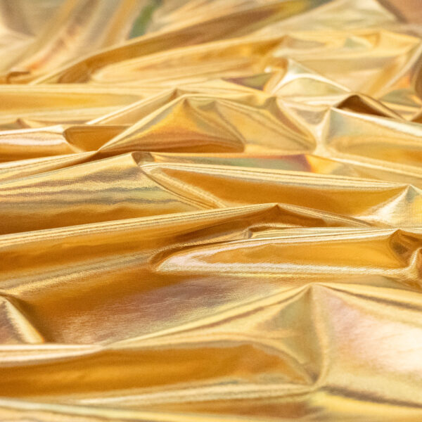 Shiny, crumpled gold foil or metallic fabric with reflective surfaces and various folds creating highlights and shadows.