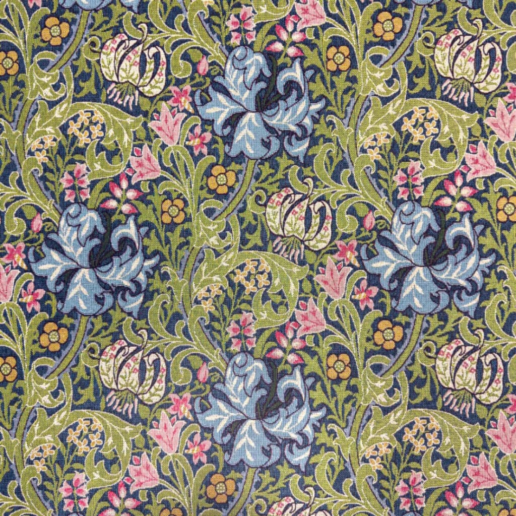 The William Morris | Pimpernel | Tapestry Fabric features a detailed floral pattern with large blue flowers, pink and yellow blossoms, and green leaves on a dark background, offering an intricate, symmetrical design with an elegant vintage appearance.