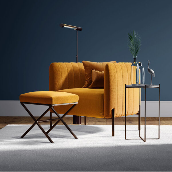 A modern living room with a mustard yellow armchair and matching ottoman, a side table holding glass vases and a metal bird sculpture, and a reading lamp, set against a dark blue wall and light rug.