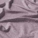 Soft purple fabric with a subtle, intricate leaf and floral pattern, shown with natural folds and gentle shadows highlighting its texture and design.