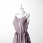 A dressmaker’s mannequin dressed in a sleeveless, light purple dress with a white measuring tape draped around its neck, set against a plain white background.