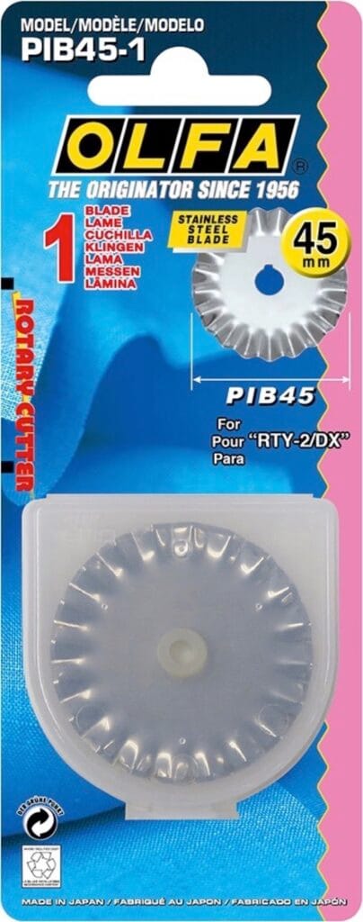 Olfa rotary cutter replacement blade (45 mm) in plastic case, packaged on blue and pink cardboard with yellow and white text, showing the blade and product details.