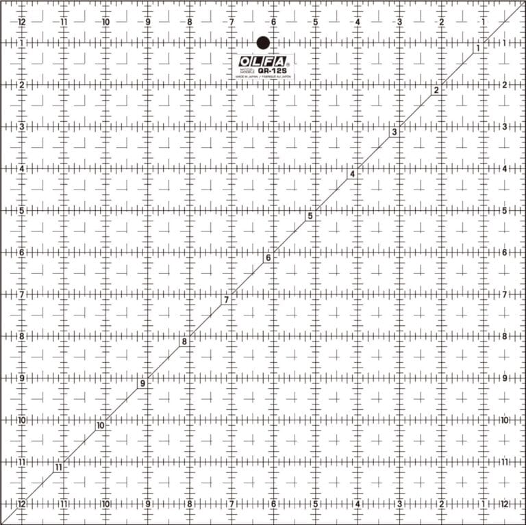 A clear OLFA QR-12S quilting ruler with black grid lines, numbers, and a diagonal line from corner to corner, marked in inches up to 12 by 12, used for measuring and cutting fabric.