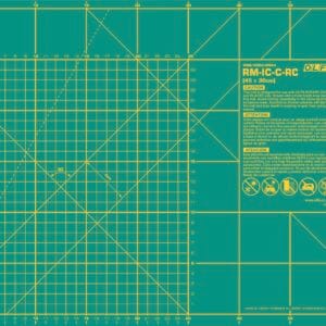 A green OLFA cutting mat marked with yellow grid lines, measurement scales in centimeters, angled guides, and warning instructions, designed for precision cutting and crafting.