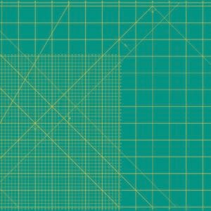 A large green self-healing cutting mat with yellow grid lines, measurement markings in inches, and angled guide lines. A label with product information is in the top right corner.