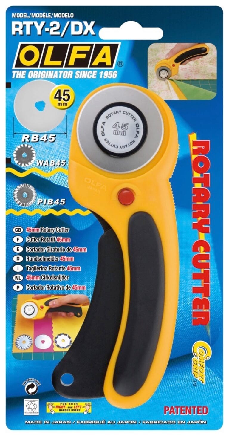 A yellow and black OLFA rotary cutter in its packaging, labeled "RTY-2/DX" for 45mm blades. The package highlights features and compatible blade types, with text in English, French, and Spanish.