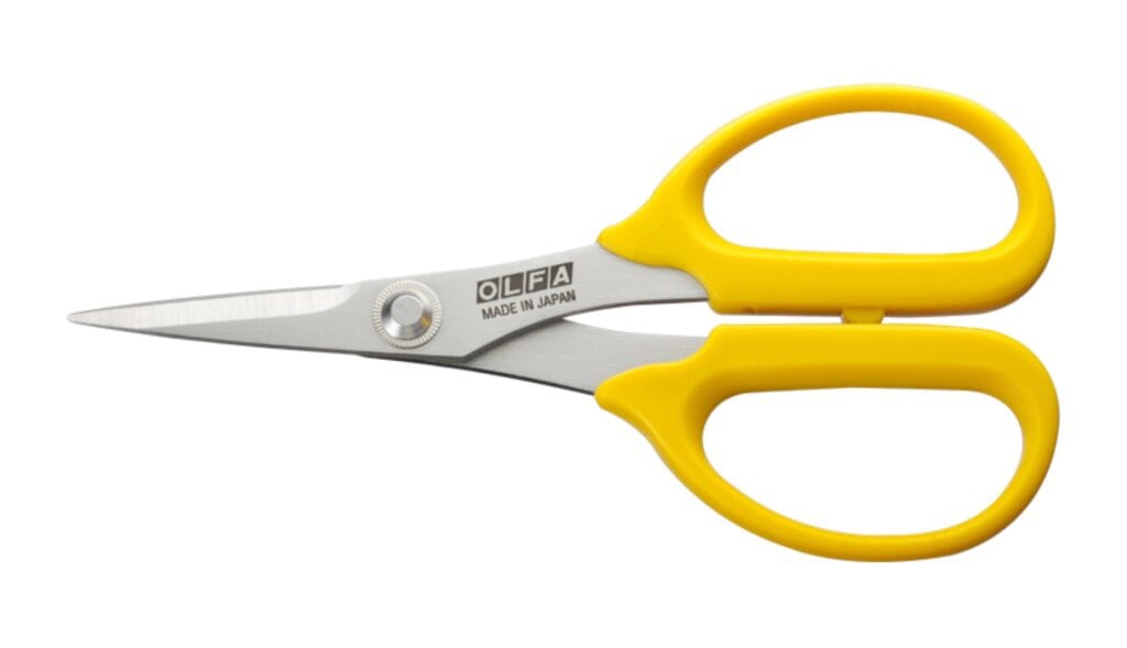 A pair of scissors with stainless steel blades and bright yellow ergonomic handles, labeled "OLFA Made in Japan," shown against a white background.