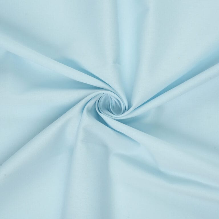 Light blue fabric with a smooth texture, arranged in a swirl pattern at the center, creating gentle folds and soft, radiating lines.