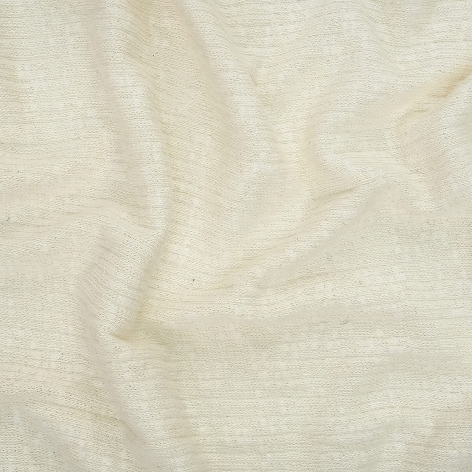 Cotton-Knitted-Cable-3 A close-up view of off-white, textured fabric with subtle horizontal lines and gentle wrinkles. The material appears soft and slightly sheer, giving a light and airy appearance.