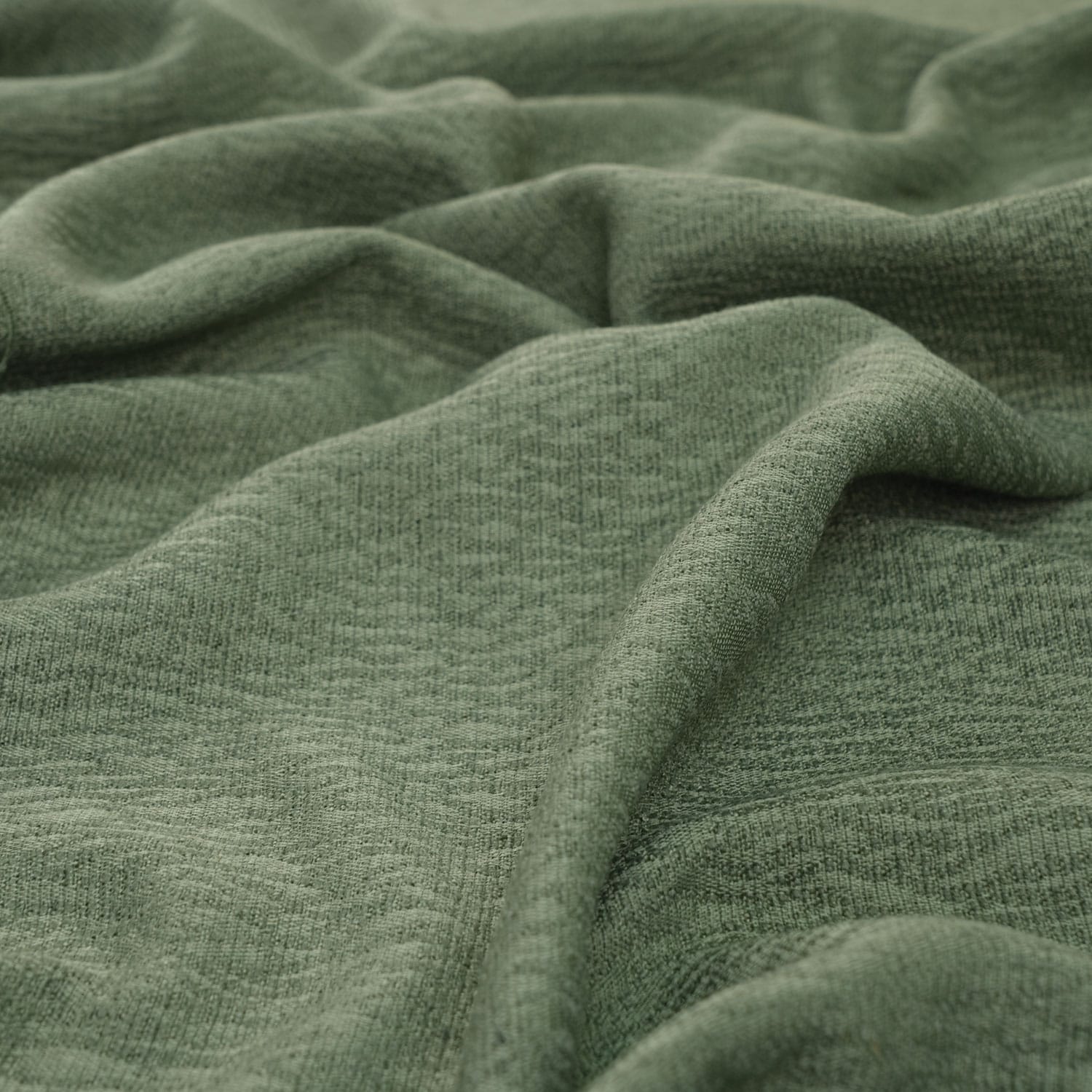 Wexford-Olive-3 A close-up view of soft, textured green fabric with gentle folds and creases throughout the surface.
