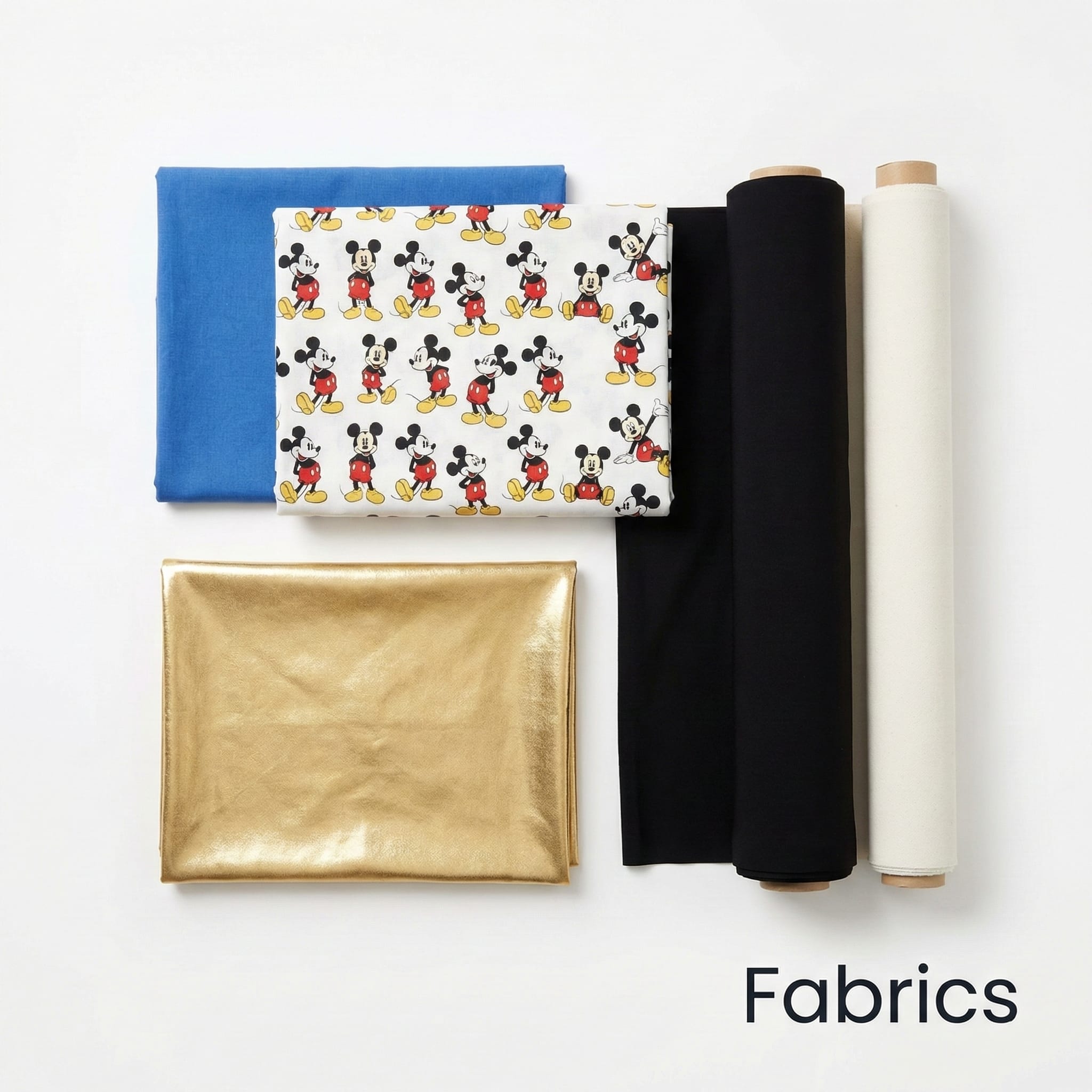 Five fabric rolls: a blue fabric, a white fabric with cartoon mouse print, two black fabrics, and one gold metallic fabric, arranged on a white background with the word 