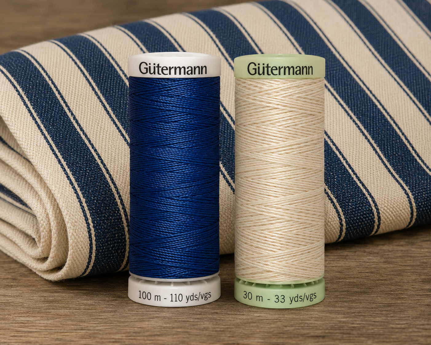 Gutermann Extra Strong thread spools in navy and cream next to canvas ticking stripe fabric